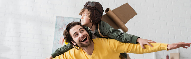 Kid in aviator costume playing with dad at home, banner © LIGHTFIELD STUDIOS