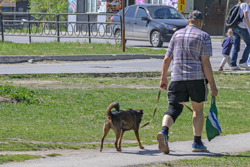 A man with a dog on a leash walks on a city sidewalk
