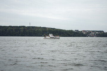 Obraz premium Excursion ship on the lake in the center of a city. White yacht with people in the middle of a large city lake.