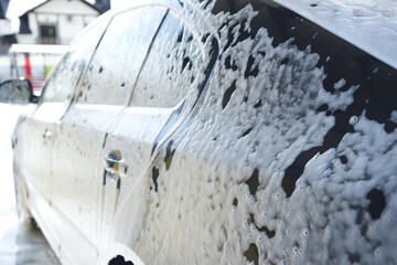 Car in white foam on a manual car wash. Gray car washed in white foam. Auto at the car wash.