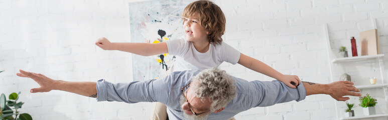 Grandparent playing with child in living room, banner