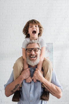 Excited kid hugging smiling grandfather