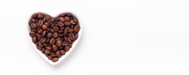 Heart shaped plate with roasted coffee beans. Horizontal banner. Top view. Copy space
