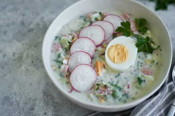 Traditional Russian cold okroshka soup served in a plate with herbs Kefir vegetable soup