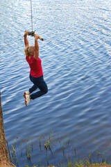 Middle aged woman in sportswear hanging on a stick with a rope above the water