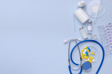 Top view of blue desk and stethoscope, drugs, medical dish glass and other tools on it.Empty space