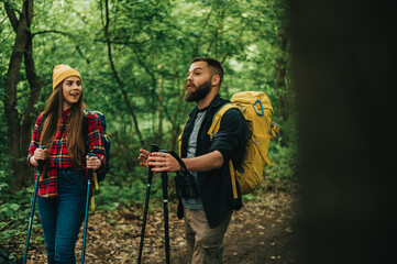 Couple of hikers using trekking poles and wearing backpacks