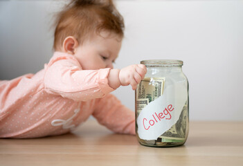 The kid is holding a piggy bank with the inscription college. Parents save money for the child's education.