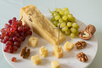 Parmesan cheese, grapes and nuts on a marble board. Appetizer. Parmigiano reggiano. Cheese plate. Side view, close up. protein diet