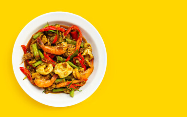 Spicy stir fried shimp, squid and pork with Thai Southern chili paste and longbean on yellow background.