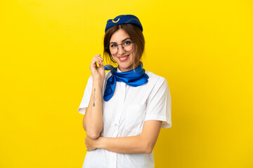 Airplane stewardess woman isolated on yellow background with glasses and happy