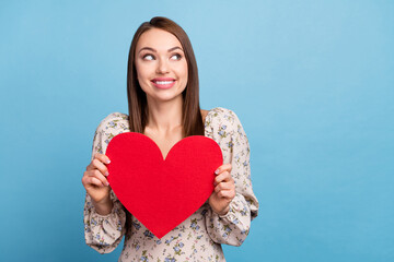 Photo of impressed brown hairdo young lady hold heart look empty space wear floral blouse isolated...