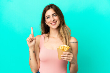 Caucasian woman holding fried chips isolated on blue background showing and lifting a finger in sign of the best