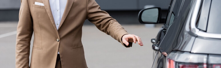 cropped view of man in beige jacket reaching car door, banner