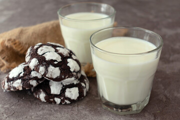 Two glasses with milk and homemade chocolate chip cookies on a gray background.