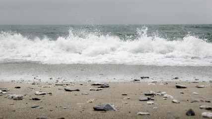 Ujęcie na wprost kamienistej plaży i spienionej fali - obrazy, fototapety, plakaty