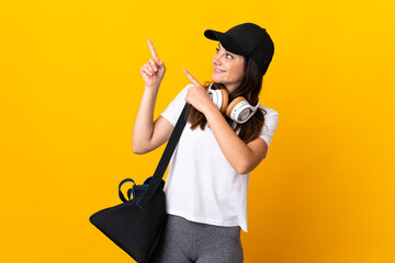 Young sport woman with sport bag isolated on yellow background pointing with the index finger a great idea