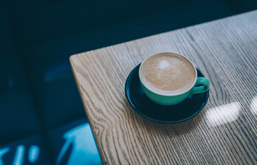 Cup of coffee on a rustic wooden table in a cafe.