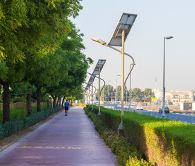 Dubai, UAE - 05.21.2021 - Middle aged man walking on jogging track in Nad Al Hamar park, early in the morning. Lamp post powered by solar panels can be seen in the picture. Outdoors
