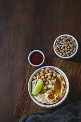 Chickpea hummus with olive oil and lime on a ceramic plate. Homemade classic hummus. Chickpea dishes, vegetarian dish.