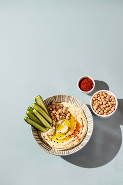 Chickpea hummus with olive oil and cucumbers on a ceramic plate. Homemade classic hummus. Chickpea dishes, vegetarian dish.