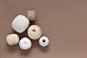 Top view of a set of skeins of natural cotton yarn in light shades for hand crocheting on a beige background. Needlework and DIY concept. Blank place for text, close up, mock up, copy space