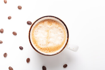 Ceramic cup with cappuccino and coffee beans on white background. Top view. Copy space