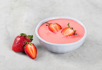 Strawberry puree soup in a bowl on a light gray background
