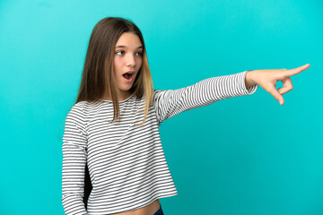 Little girl over isolated blue background pointing away