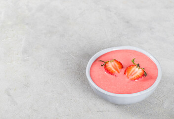 Vegan strawberry soup in a bowl on a light gray background copy space