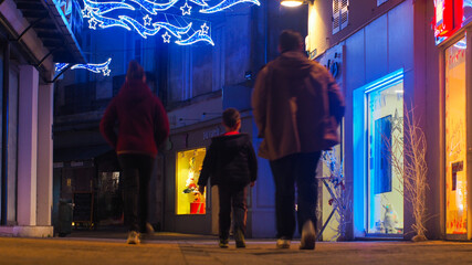 Un père, une mère, et son fils, marchent ensemble dans une rue de Marmande, un soir de Décembre