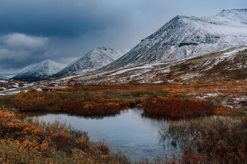 Autumn tundra and cold river on the background of  misty snow-capped mountains, Arctic, Kola Peninsula