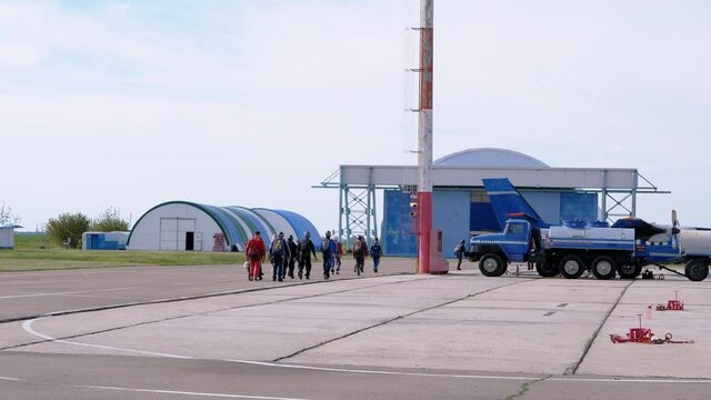 Team Parachutists is Walking by aerodrome to Airplane before Takeoff in Airport.. Athletes footsteps in overalls with backpacks. Skydiving in clear weather with blue sky, clouds. Extreme sport. 4K.