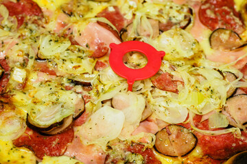 Close-up of sausages and onions on pizza with plastic stand.