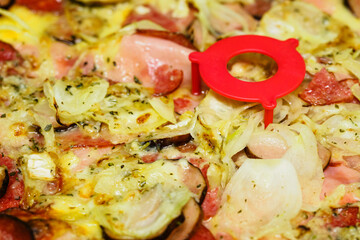 Close-up of sausages and onions on pizza with plastic stand.