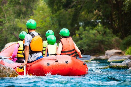 Group of family are rafting on the river turbulent flow. Extreme and enjoyment sport.