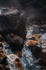 Natural sulfuric hot springs. Hot water runs down the stones. Philippines. Vertical photo. 