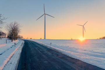 road and wind turbines in winter at sunset