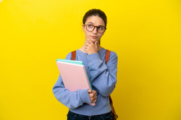 Student kid woman over isolated yellow background having doubts