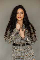 Portrait of beautiful young woman with long dark curly hair on gray background. hair and face care concept.
