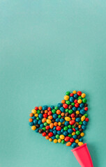 Obraz na płótnie Canvas Chocolate multicolored heart candy dragee on a blue background