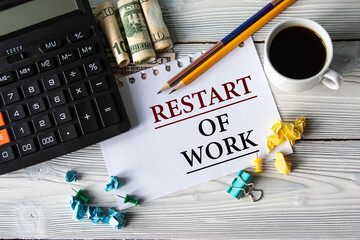 RESTART OF WORK - words on a white sheet against the background of a calculator, banknotes, cups of...