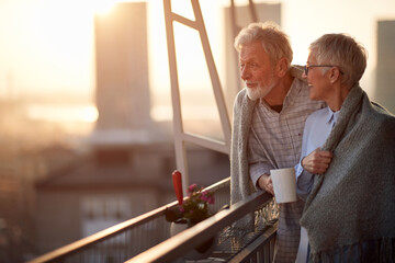 Naklejka premium An elderly couple enjoying a view on the city from the terrace of their appartment. Spouses, pensioners, together, home