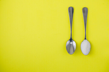 Sugar-replacement tablet of stevia and sugar in tea spoons lying in same directions on bright...