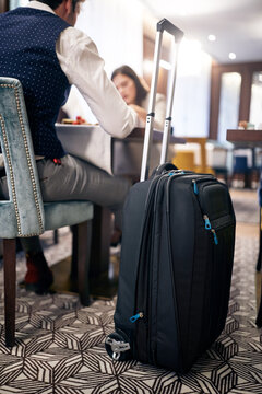 image of wheeled suitcase in hotel with people in the background having lunch