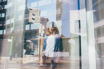 Double exposure between a young beautiful blonde millennial woman pensive and the city