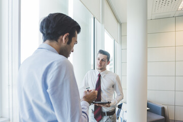 Obraz premium Multiethnic businessman indoor office using tablet talking meeting