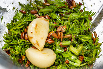 Ingredientes frescos para preparo de molho pesto sustentável: rama da cenoura, sementes de...