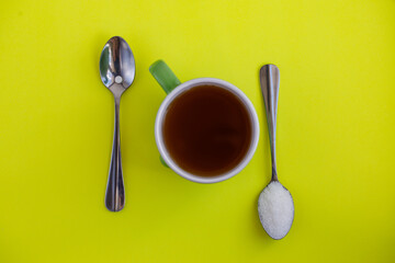 Sugar-replacement tablet of stevia and sugar in tea spoons lying in opposite directions on bright...