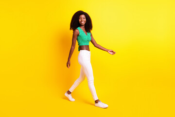 Full length body size photo funky girl smiling wearing white pants green top sneakers isolated vibrant yellow color background